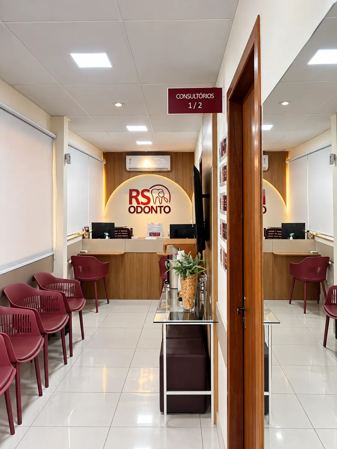Recepção da RS ODONTO com balcão em madeira, poltronas vinho e logo iluminado